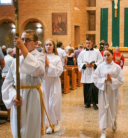 altar servers and priests recess from a church