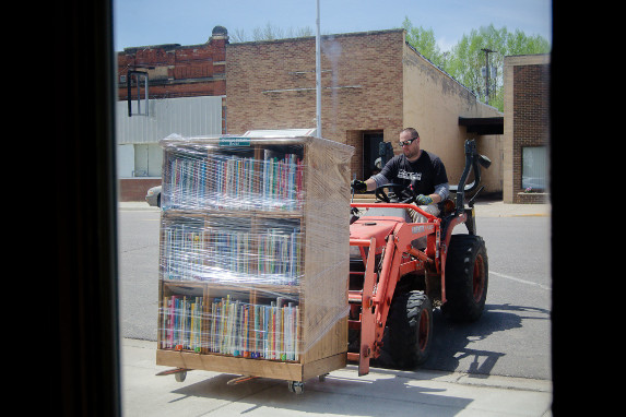 A skid steer moves a bookshelf