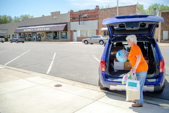 A librarian unloads a globe out of the back of a vehicle