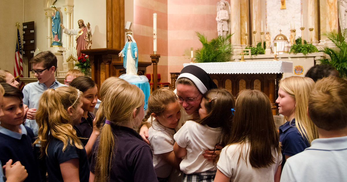 children hug a nun in habit